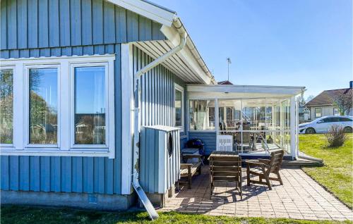 a blue house with a patio with a table and chairs at Nice Home In Ljungby With Wifi in Ljungby