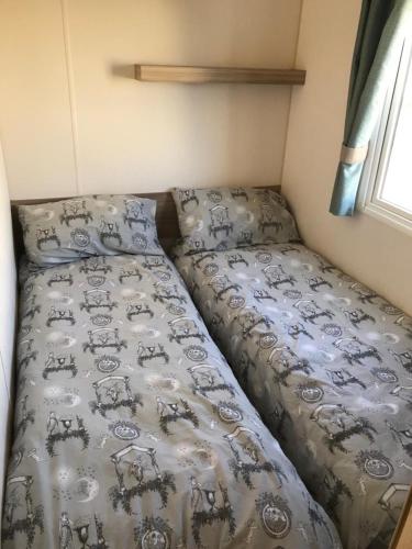 a bed in a small room with a comforter at TSCaravan, Haven, Golden Sands in Mablethorpe