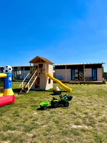 a house with a playground with a slide and play equipment at Resto domki letniskowe in Sarbinowo
