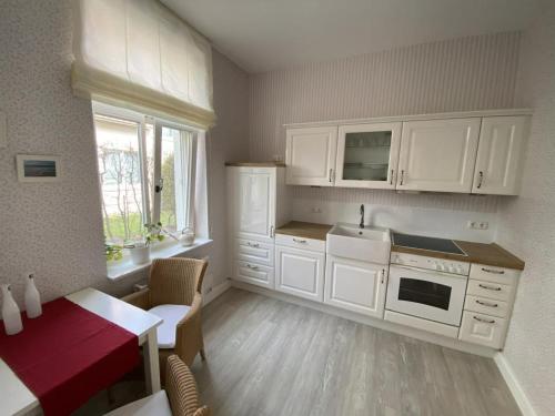 a kitchen with white cabinets and a table with a red table at Fewo in Villa mit Seeblick in Plau am See