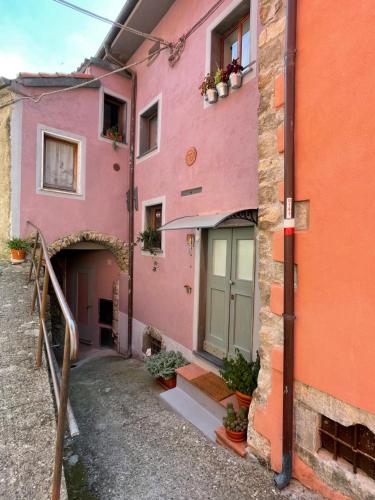 a pink building with a green door and some plants at La Casa nel Borgo in Fosdinovo