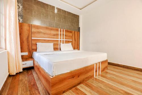 a bedroom with a bed with a wooden headboard at FabHotel Green Origins in Dharamshala