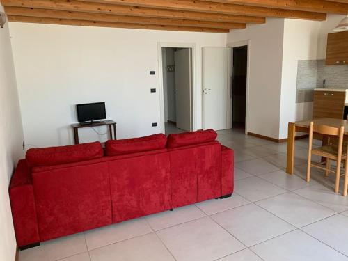 um sofá vermelho numa sala de estar com uma mesa em LA CASA DI MARTINA em Castelnuovo del Garda