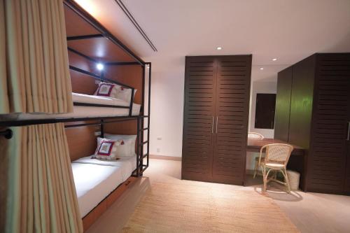 a bedroom with two bunk beds and a desk at Selina Serenity Rawai Phuket in Rawai Beach