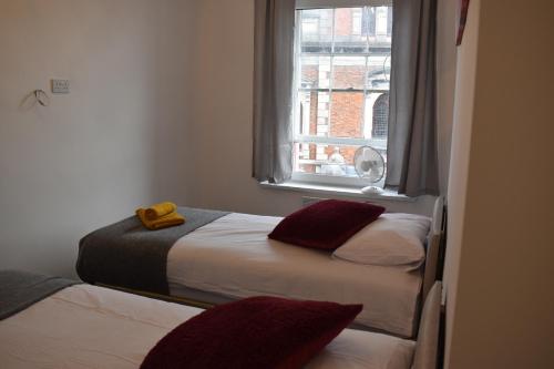 twee bedden in een kleine kamer met een raam bij Camri Room in Denbigh