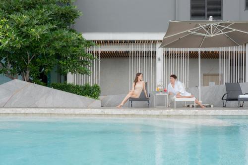 two women sitting in chairs next to a swimming pool at Holiday Inn & Suites Siracha Laemchabang, an IHG Hotel in Si Racha