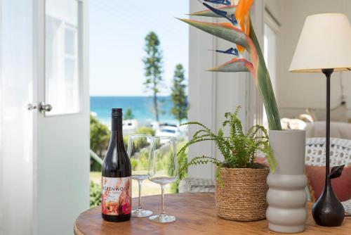a bottle of wine sitting on a table with two glasses at Mollymook Beach View in Mollymook