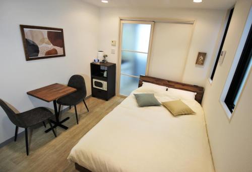 a bedroom with a bed and a table with chairs at Apartment Hotel Hakata in Fukuoka