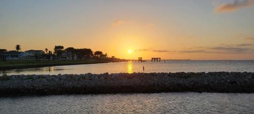 a sunset over a body of water with the sun setting at Las Casitas on Magnolia Beach - Casita B in Port Lavaca