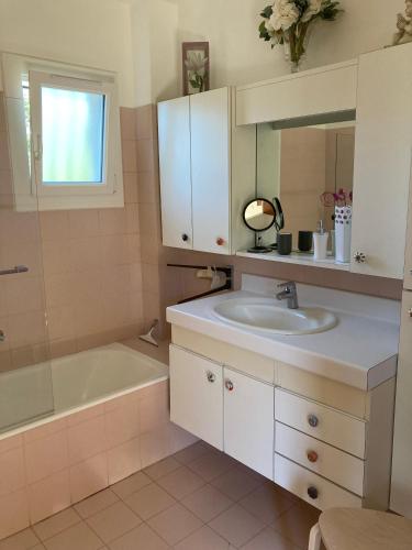 une salle de bain avec un lavabo, un miroir et une baignoire dans l'établissement Haut de villa avec terrasse privative jardin et parking tout près des plages, à Toulon