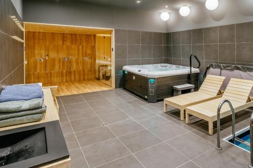 ein Badezimmer mit einer Badewanne, einer Bank und einem Stuhl in der Unterkunft Rákóczi Hotel, Tábor és Rendezvényközpont in Sátoraljaújhely