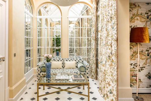 uma sala de estar com um sofá e janelas em Saint James Paris em Paris