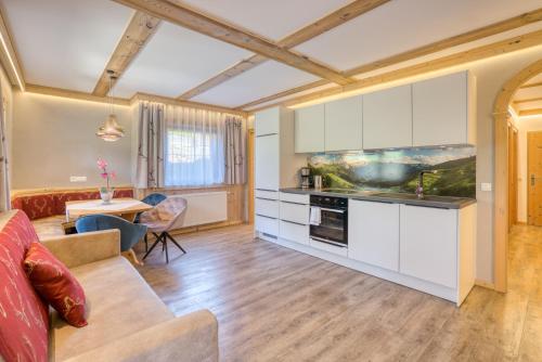 a kitchen with white cabinets and a living room at Appartement Hofmann in Königsleiten