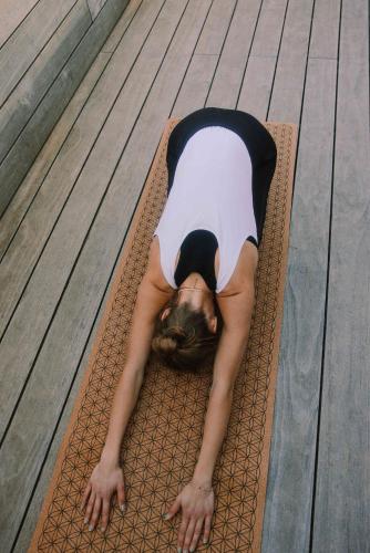 a woman laying on a mat on a wooden deck at Stadthotel Brunner in Schladming