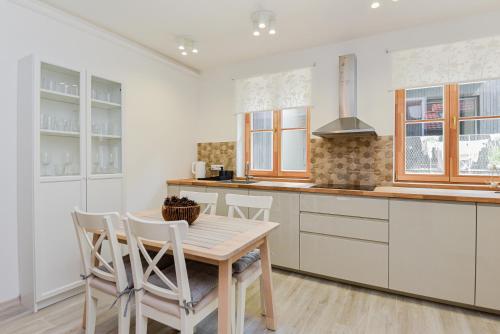 a kitchen with white cabinets and a wooden table and chairs at Sengirės kotedžai Juodkrantė in Juodkrantė
