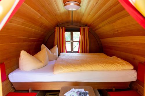 Cama pequeña en habitación de madera con ventana en Sporthotel Wernigerode, en Wernigerode