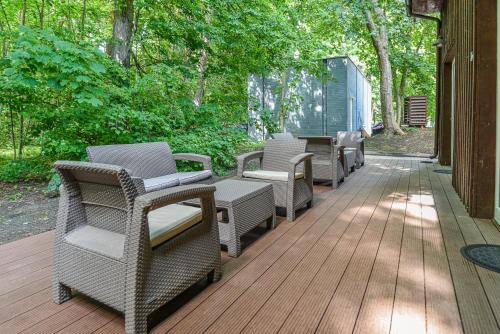 a row of wicker chairs sitting on a wooden deck at Sengirės kotedžai Juodkrantė in Juodkrantė