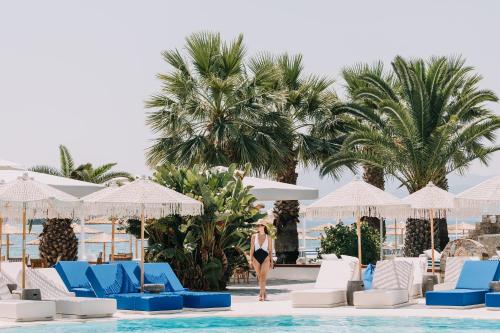 a woman standing next to a pool at a resort at Brown Beach Evia Island, All Inclusive in Eretria, a member of Brown Hotels in Eretria