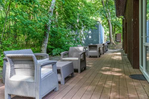 a row of wicker chairs sitting on a deck at Sengirės kotedžai Juodkrantė in Juodkrantė