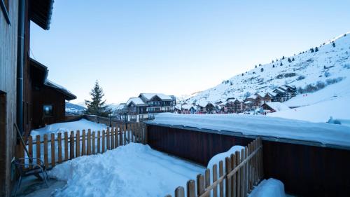 a fence covered in snow next to a mountain at Hôtel Club "Les Carrettes" in Valmeinier