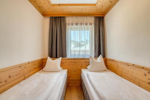 two beds in a room with a window at Appartement Hofmann in Königsleiten