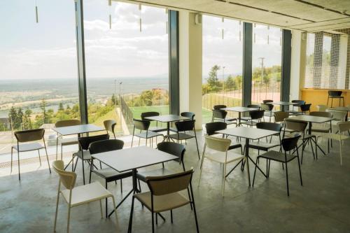 a room with tables and chairs and large windows at Rákóczi Hotel, Tábor és Rendezvényközpont in Sátoraljaújhely