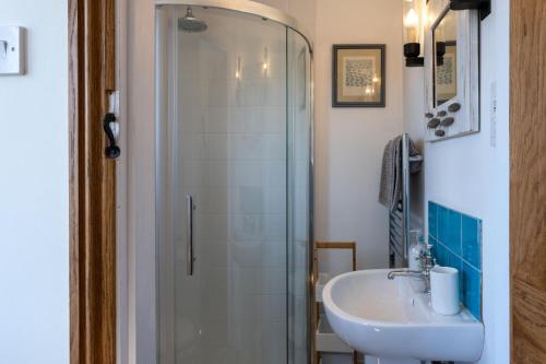 een badkamer met een wastafel en een glazen douche bij Heather Cottage in Brockenhurst
