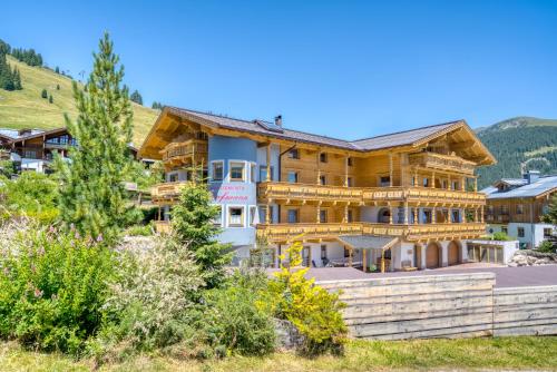 a large wooden house with a mountain at Appartement Hofmann in Königsleiten