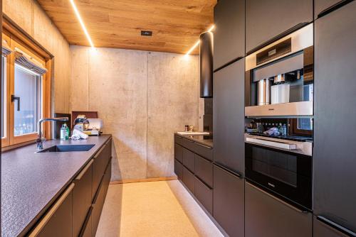 a kitchen with black cabinets and a sink at Chalet Bergfreund in Valdaora