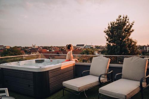 uma mulher sentada numa banheira de hidromassagem numa varanda em Hotel Glory em Oradea