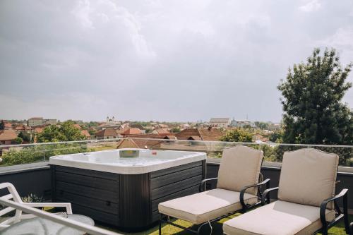 a hot tub on a balcony with two chairs at Hotel Glory in Oradea