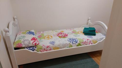 a small bed with a floral bedspread and a green bag on it at CASA DI MIMMA casa vacanze in Reggio Calabria