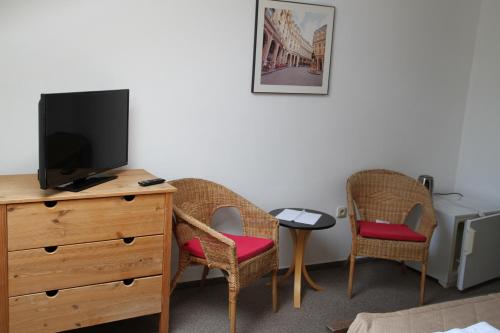 a room with two chairs and a dresser with a television at Penzión Malý Dvor in Štúrovo