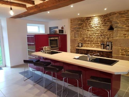 a kitchen with red cabinets and a stone wall at La grange de Victor 12/14 pers - Mont-Saint-Michel in Céaux