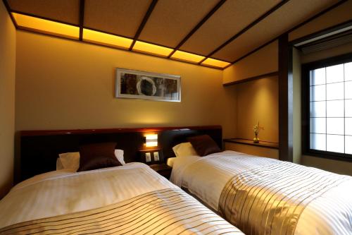 a bedroom with two beds and a window at Oyado Ikegami in Uozu