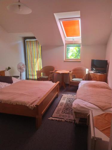 a bedroom with two beds and a table and a window at Penzión Malý Dvor in Štúrovo