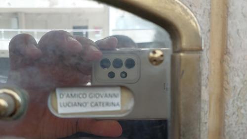 a hand holding a remote control in front of a door at Attico Sottovento in Reggio Calabria