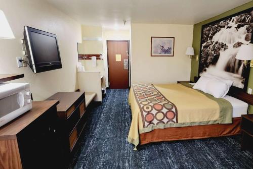 a hotel room with a bed and a flat screen tv at Super 8 by Wyndham Rawlins Wyoming in Rawlins