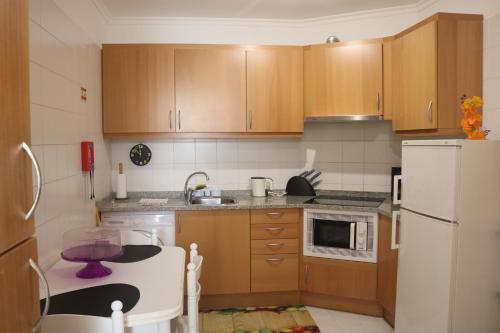 a kitchen with wooden cabinets and a white refrigerator at Garajau Terrace Orchids in Caniço