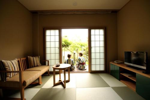 a living room with a couch and two children looking out the door at Oyado Ikegami in Uozu