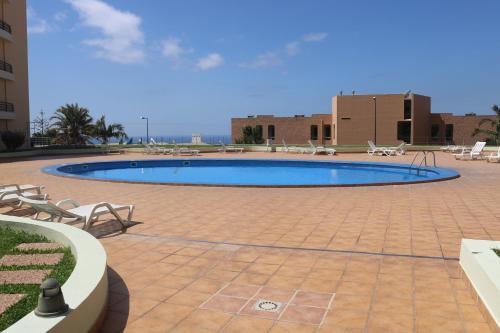 a large swimming pool in a courtyard with chairs at Garajau Terrace Orchids in Caniço