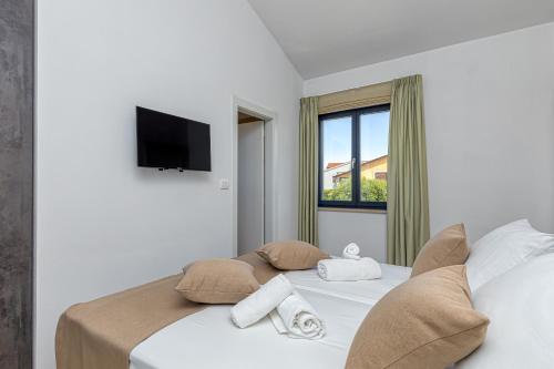 a bedroom with a white bed with a tv on the wall at Villa Istria Vabriga in Vabriga