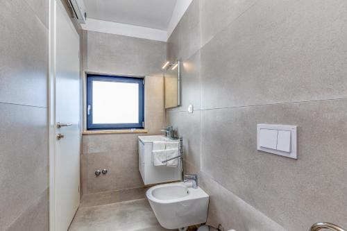 a bathroom with a toilet and a sink and a window at Villa Istria Vabriga in Vabriga