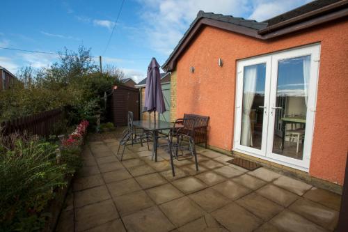 eine Terrasse mit Tisch und Stühlen und einem Fenster in der Unterkunft Goitre Bach Cottage in Aberaeron