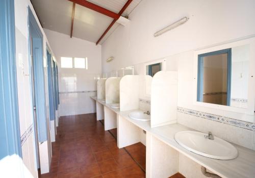 uma casa de banho com três lavatórios e uma fila de espelhos em Kampaoh Valdevaqueros em Tarifa