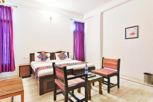 FabHotel Gitanjali في جايبور: غرفة نوم بسرير وطاولة وكراسي