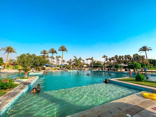 ein Pool in einem Resort mit Menschen im Wasser in der Unterkunft Sakkara Country Club in Kairo