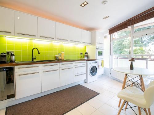 a kitchen with white cabinets and yellow tiles at Pass the Keys - Modern and spacious flat in South Central London in London