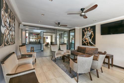 sala de estar con sofá, mesa y sillas en Regent Select Hotel, en Gaborone