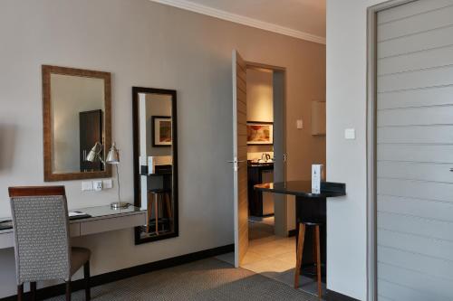 a room with a desk and a table and a mirror at Regent Select Hotel in Gaborone